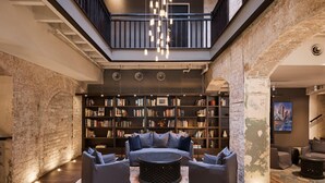 Interior moderno com área de estar central, teto alto, paredes de tijolo aparente e um mezanino.