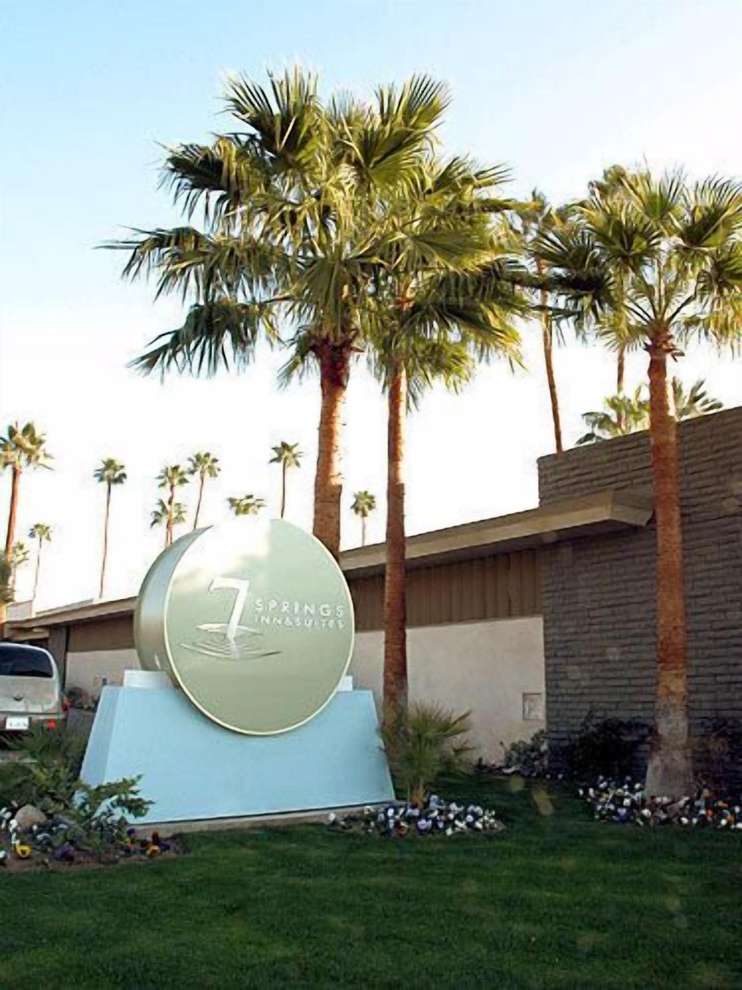Señal de '7 Springs Inns & Suites' con palmeras al fondo.