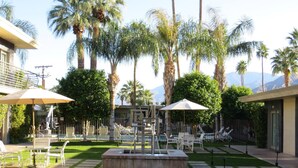 A well-maintained outdoor patio area with a central water feature, surrounded by palm trees and lounge chairs. - 7 Springs Inn & Suites (Palm Springs)