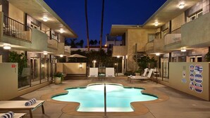 A hotel courtyard with a swimming pool, lounge chairs, and a building with balconies. - 7 Springs Inn & Suites (Palm Springs)
