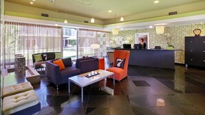 A modern lobby with seating areas, a reception desk, and a view of the outdoors. - 7 Springs Inn & Suites (Palm Springs)