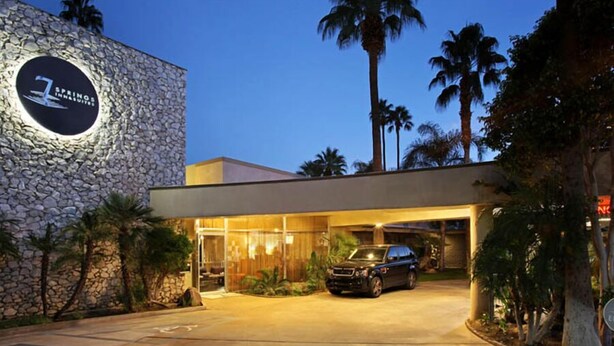 A hotel entrance with a stone facade, a parked SUV, and palm trees in the background. - 7 Springs Inn & Suites (Palm Springs)