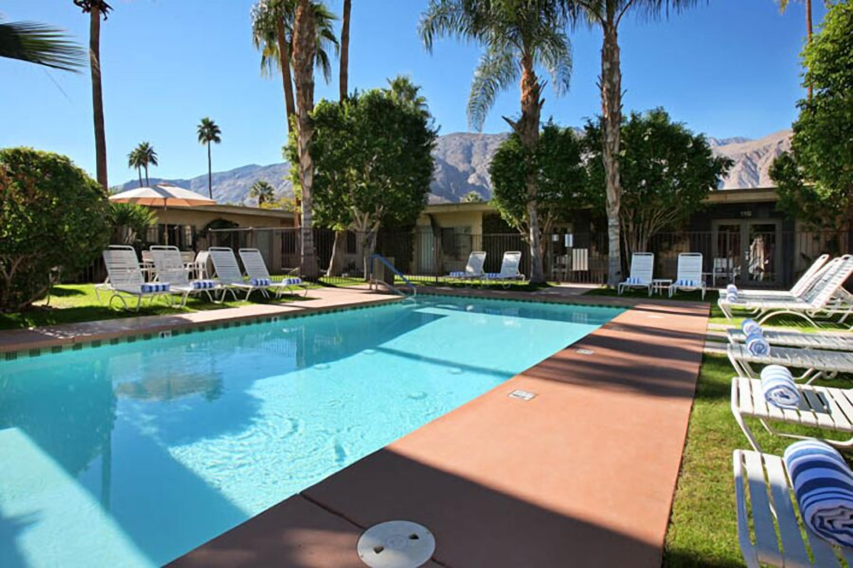 A pool area with lounge chairs and a view of mountains.
