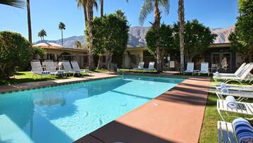 A pool area with lounge chairs and a view of mountains.