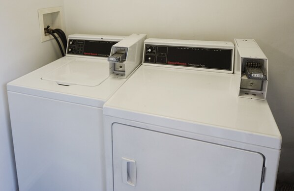 A laundry area with three washing machines and a dryer.