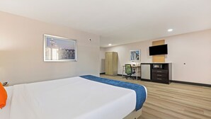 A hotel room with a bed, a desk, a television, and a wardrobe.