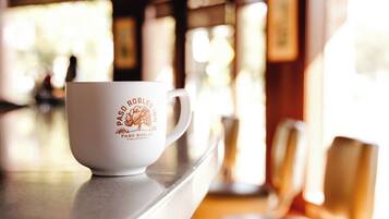 A white coffee cup with text on a table in a cafe.