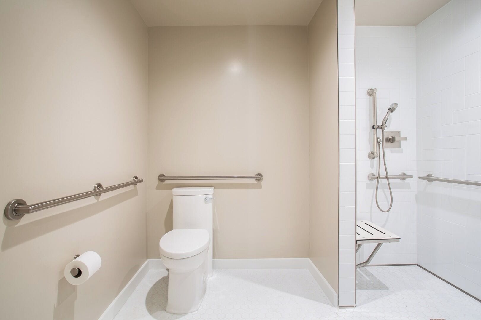 Une petite salle de bain moderne équipée de toilettes, d’une douche et d’une barre d’appui.