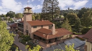 A large brick building with a tower, a covered patio, and a parking area.