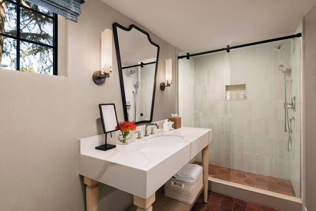 A modern bathroom with a large mirror, two sinks, and a glass-enclosed shower.
