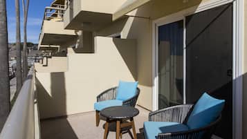 Un balcon doté de meubles en osier et d’une porte vitrée.