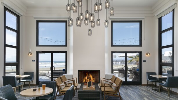 Un salón moderno con chimenea, sillones de cuero y grandes ventanales con vistas a la playa.