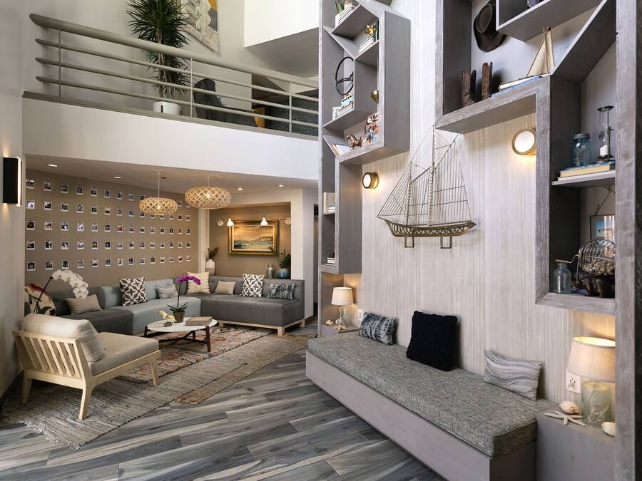 A spacious living area with a high ceiling, a built-in bookshelf, and a decorative wall.