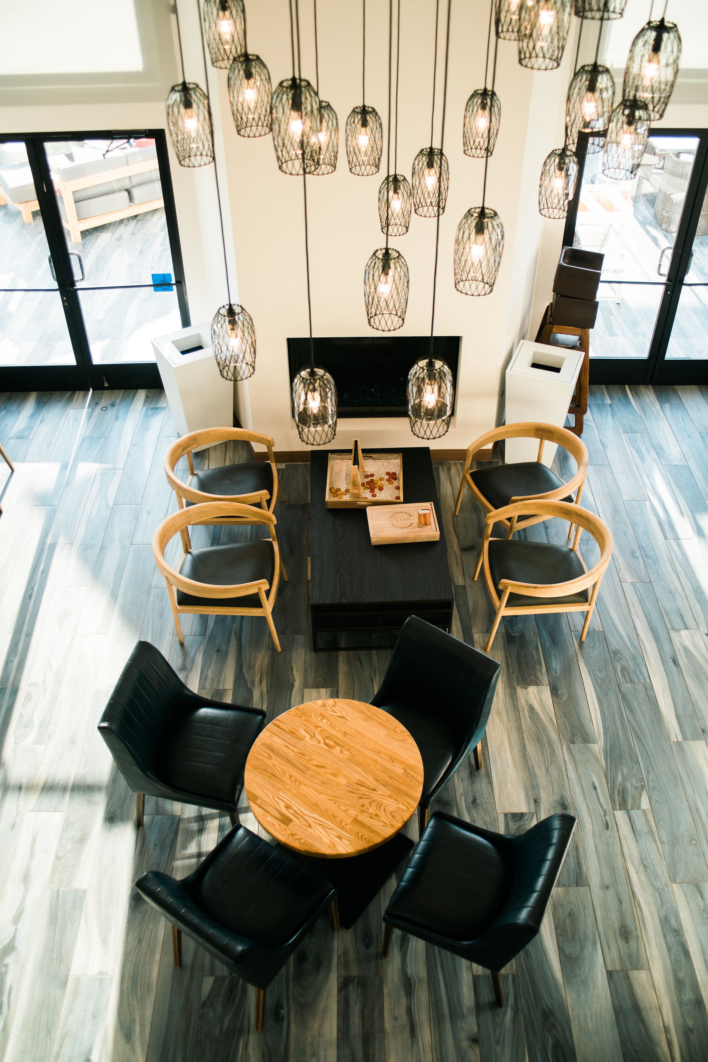 A modern interior with a round wooden table surrounded by four chairs, a black sofa, and a fireplace.