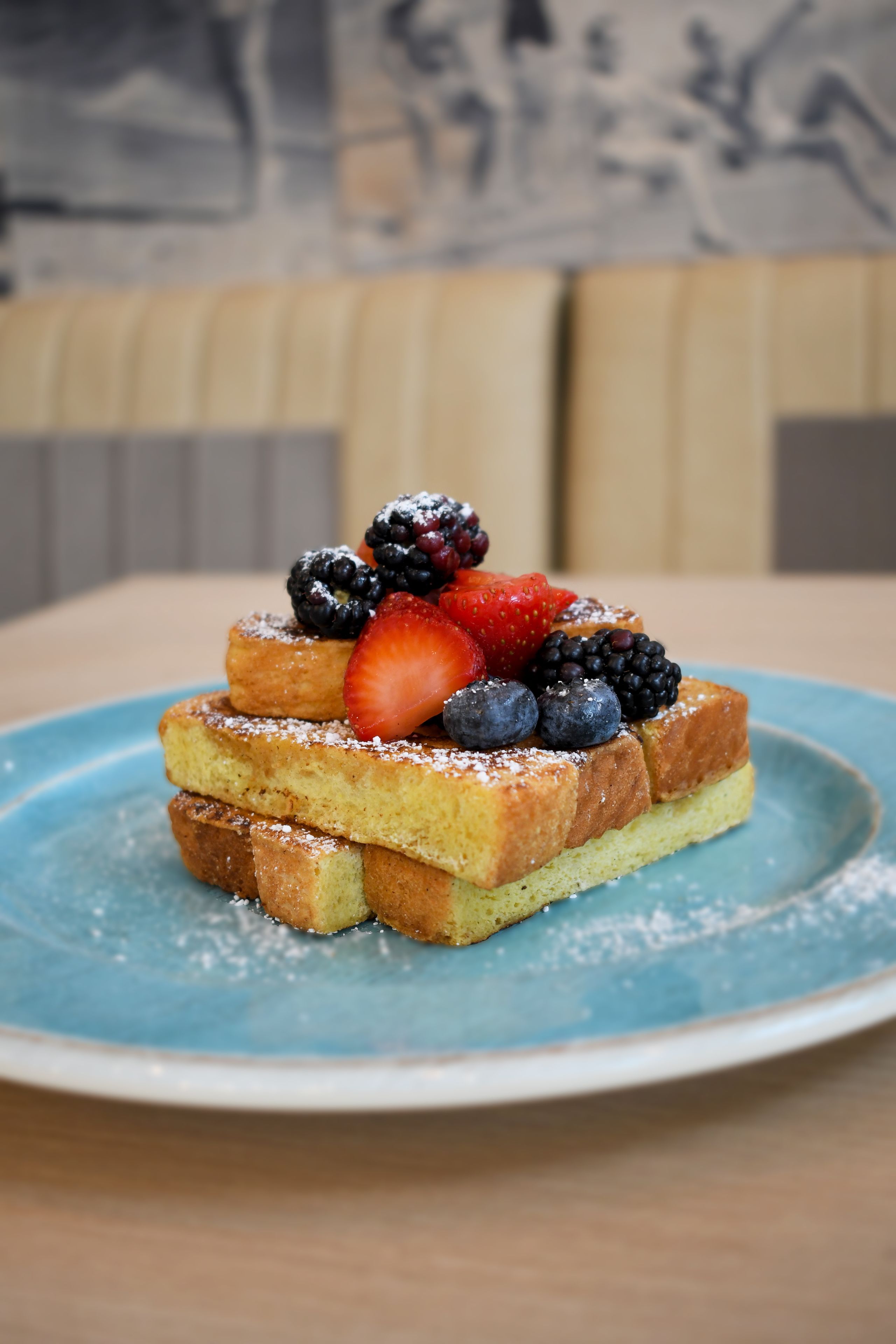 A stack of French toast with berries on a blue plate.