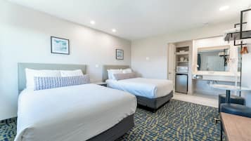 Habitación de hotel con dos camas, baño y kitchenette.