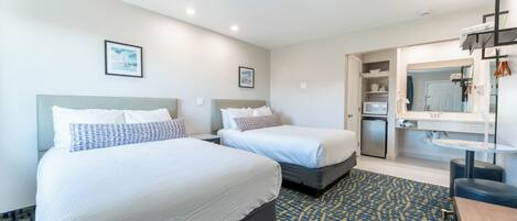 A hotel room with two beds, a bathroom, and a kitchenette.