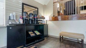 A hotel room with a coffee station, a bench, and a fireplace.
