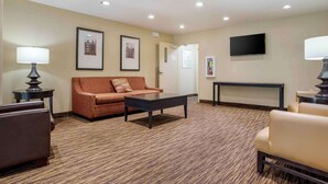 A hotel room with a sofa, armchairs, a coffee table, a TV, and framed pictures on the wall.