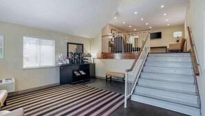 A spacious living area with a staircase leading to an upper level, a black entertainment unit, and a striped area rug.