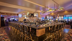 A bar area with multiple gaming machines, a bar counter, and several bar stools.
