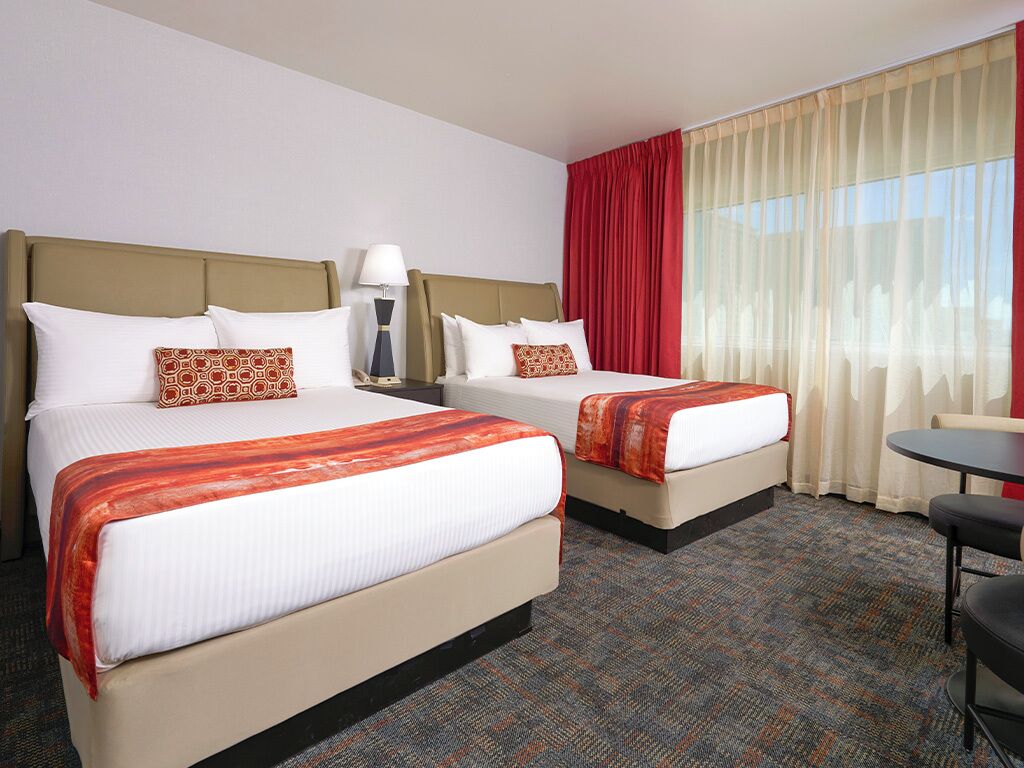 A hotel room with two beds, a desk, and a chair.