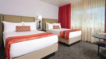 A hotel room with two beds, a desk, and a chair.