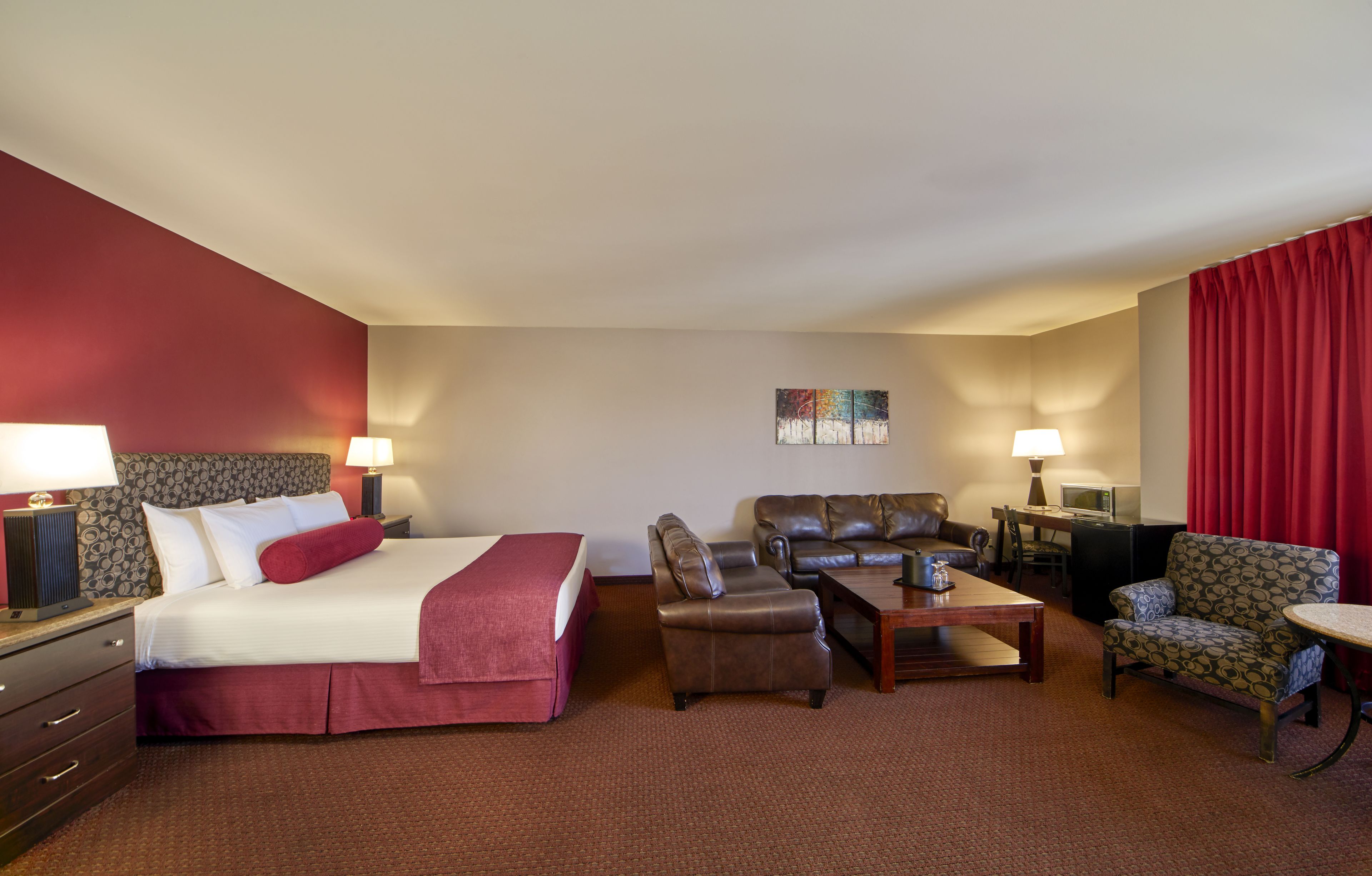 Una habitación de hotel con una cama, dos sofás, una mesita de centro y un escritorio con lámpara.