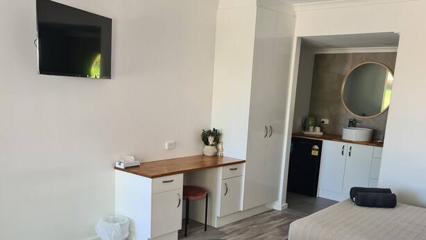 A modern bedroom with two beds, a desk, and a kitchenette. - Alice Motor Inn (East Side)