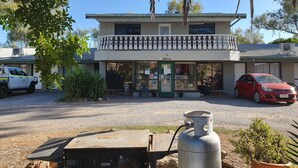 A two-story building with a reception area, a balcony with decorative railings, and a parked car. - Alice Motor Inn (East Side)