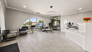 A hotel reception area with a modern design, featuring a reception desk, seating area with sofas, and a large window offering a view of the outside. - Heritage Inn Express Roseville (Roseville)