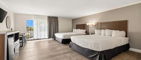 Habitación de hotel con dos camas, un escritorio y un balcón con cortinas.