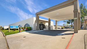 A Heritage Inn Express building with a covered parking area and a sign indicating a 12 ft height limit. - Heritage Inn Express Roseville (Roseville)