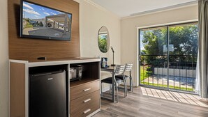 A modern kitchen with a built-in refrigerator, a flat-screen TV mounted above the counter, and a dining area with a table and chairs. - Heritage Inn Express Roseville (Roseville)