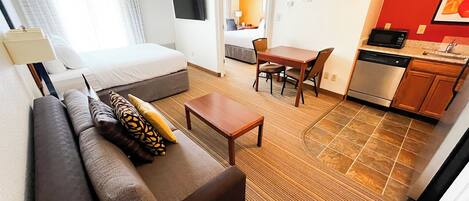 A hotel room with a bed, sofa, dining table, and kitchenette.