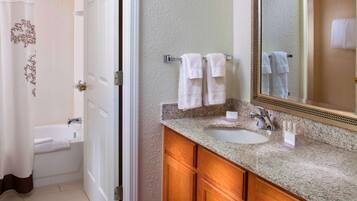 A bathroom with a sink, mirror, and towel rack.