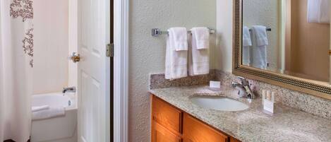 A bathroom with a sink, mirror, and towel rack.