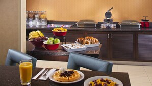 Un buffet de petit-déjeuner proposant divers plats et des gaufres.