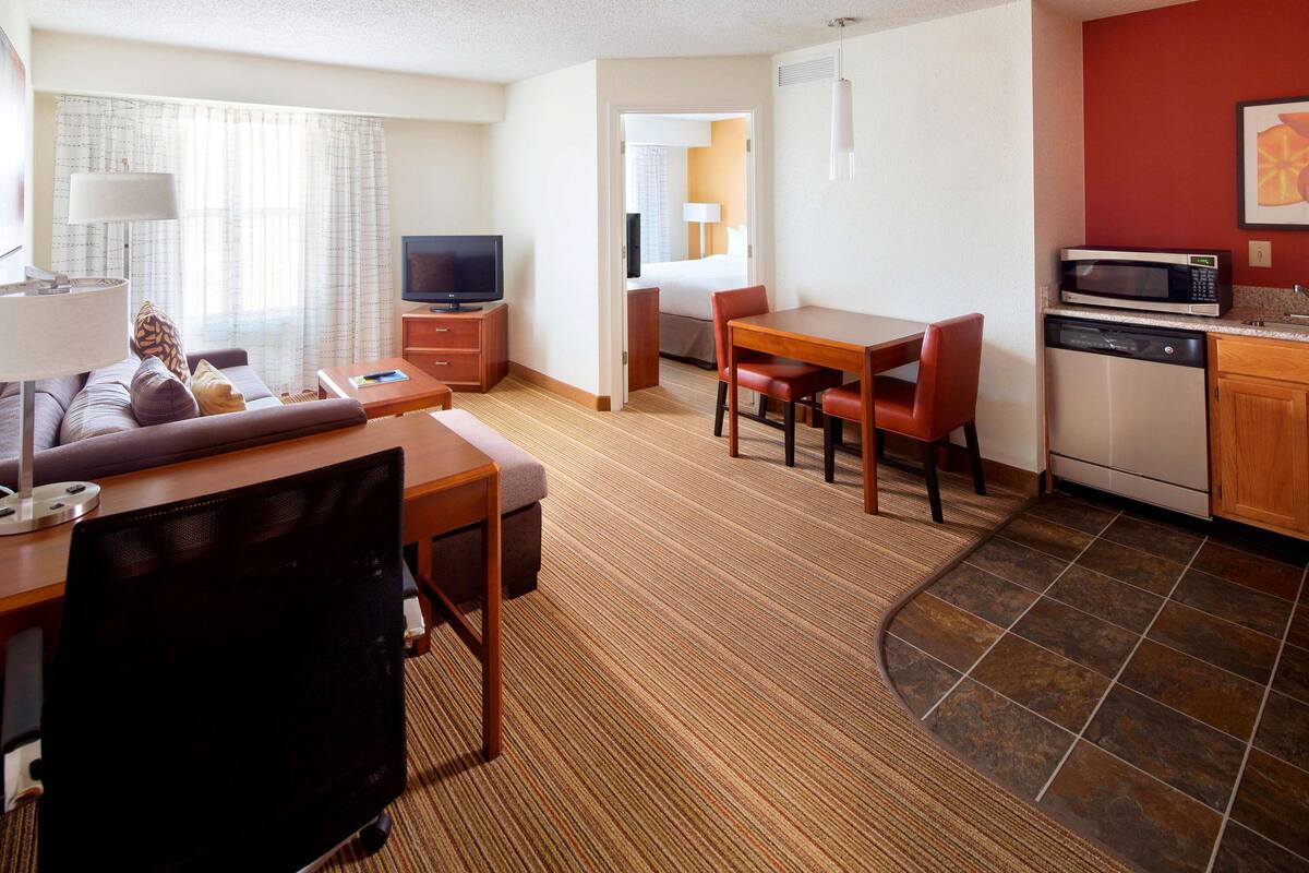 Une chambre d’hôtel comprenant un coin salon, une table à manger, une cuisine et un téléviseur.