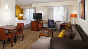 Une chambre d’hôtel comprenant un lit, un bureau avec un ordinateur, une télévision, un canapé et une table à manger avec des chaises.
