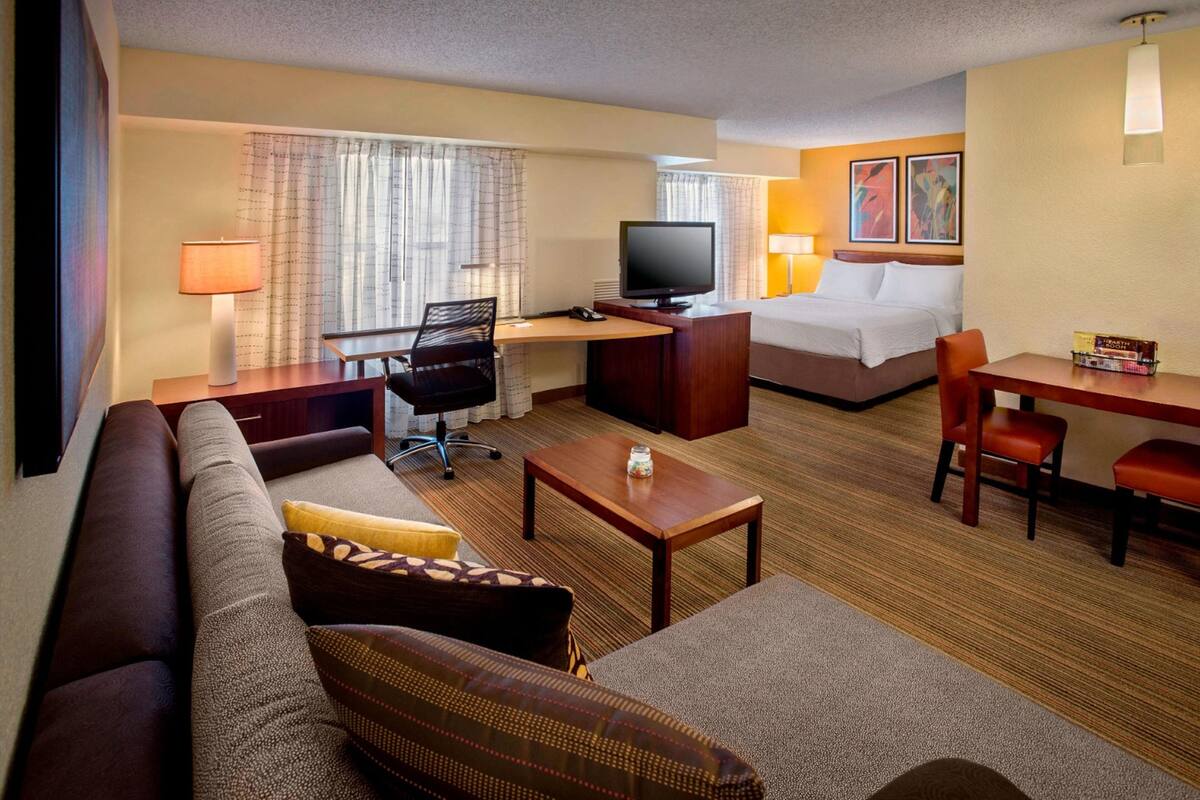 Une chambre d’hôtel équipée d’un canapé, d’un bureau avec un ordinateur, d’un lit et d’une télévision.