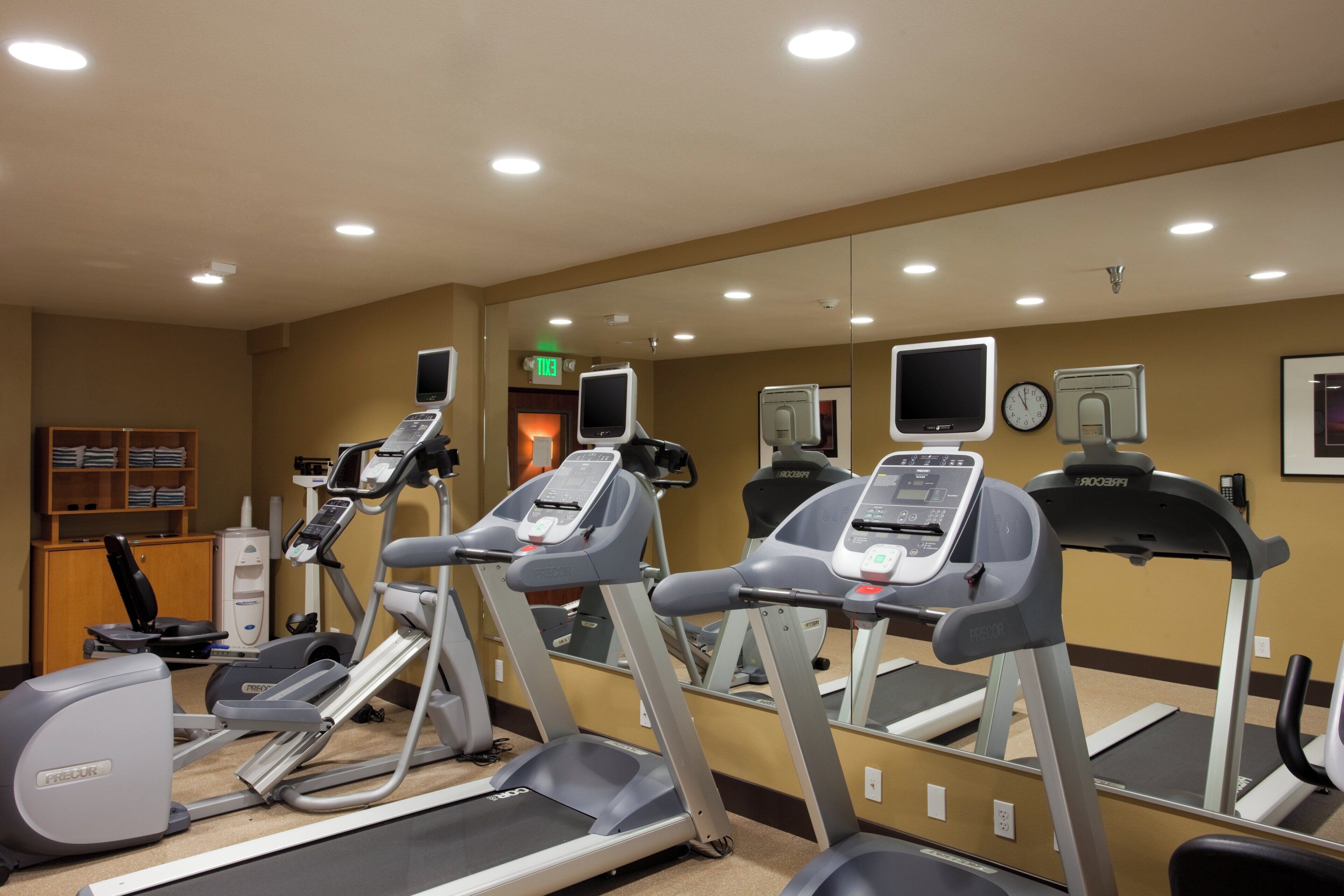 A gym with treadmills, stationary bikes, and a mirrored wall.