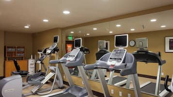 A gym with treadmills, stationary bikes, and a mirrored wall.