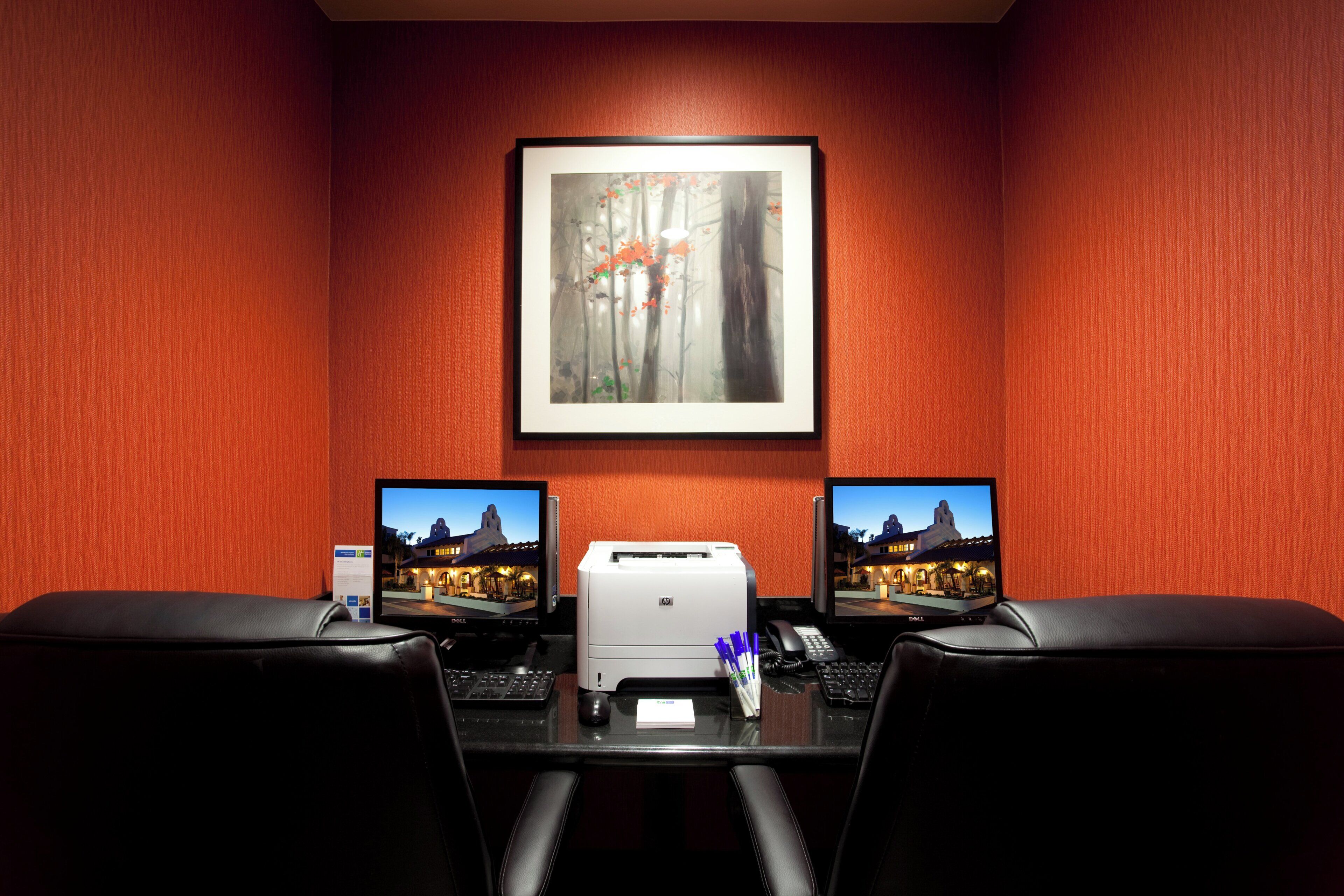 A conference room with two monitors, a printer, and a telephone on a desk.
