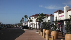 A street lined with palm trees and a building with a Planet Beauty sign. - Holiday Inn Express San Clemente N – Beach Area by IHG (San Clemente)