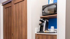 Ein Flur mit einem Holzschrank und einer kleinen Küchenzeile mit Mikrowelle und Kaffeemaschine.