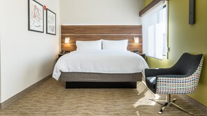 A modern hotel room with a large bed, a chair, and two wall-mounted lamps. - Holiday Inn Express San Clemente N – Beach Area by IHG (San Clemente)