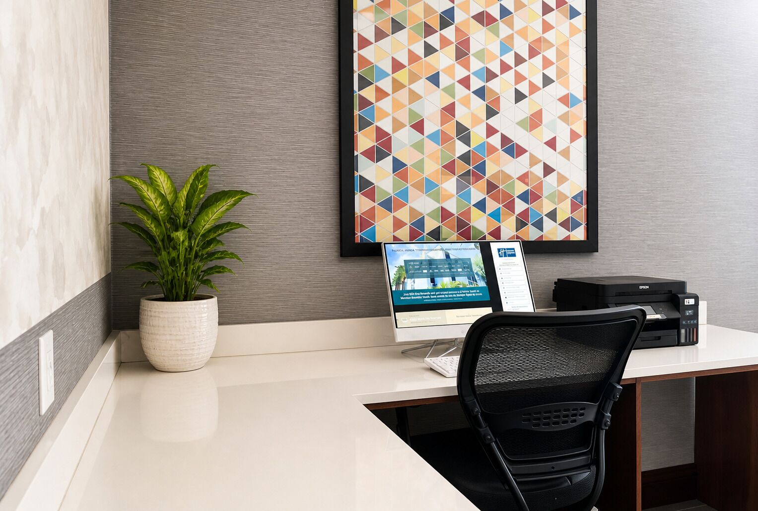 A modern office desk with a computer, printer, and a potted plant.