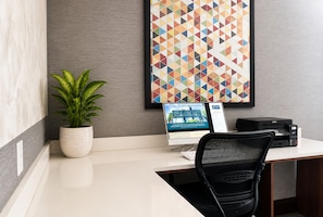 A modern office desk with a computer, printer, and a potted plant.