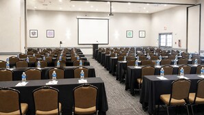 Ein Konferenzraum mit Tischen, Stühlen, einer Projektionsleinwand und einem Bildschirm für Präsentationen.